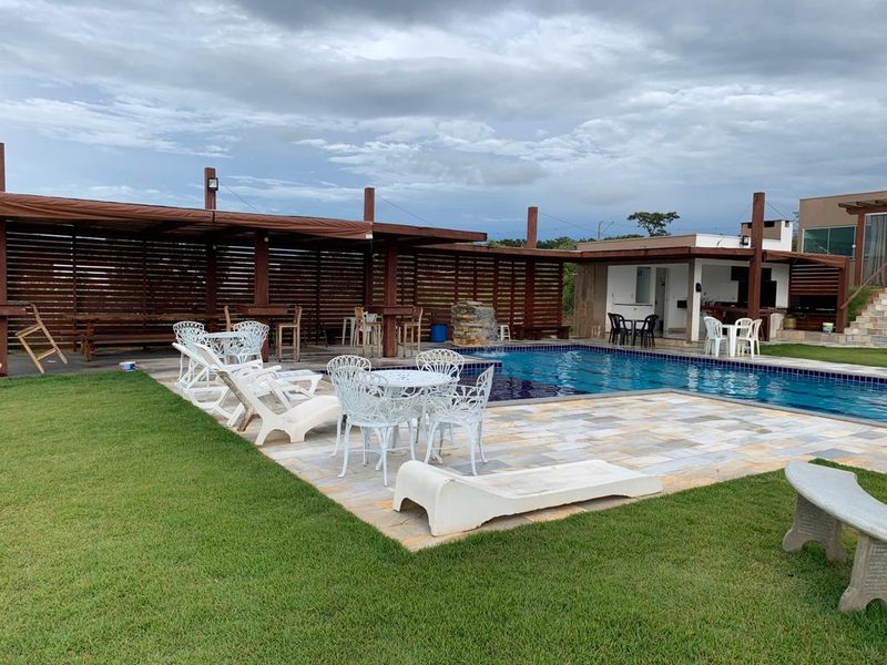 Piscina com espreguiçadeiras e área coberta ao lado
