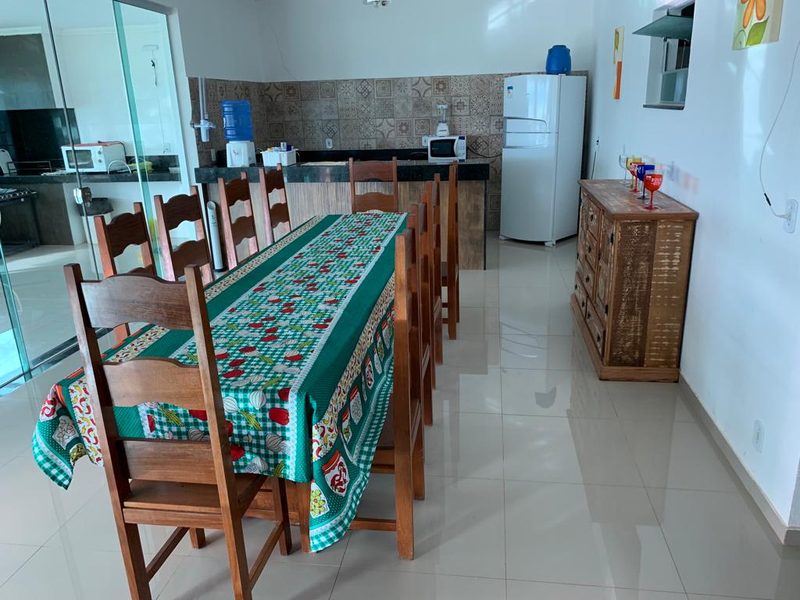 Mesa grande de refeição com a cozinha ao fundo